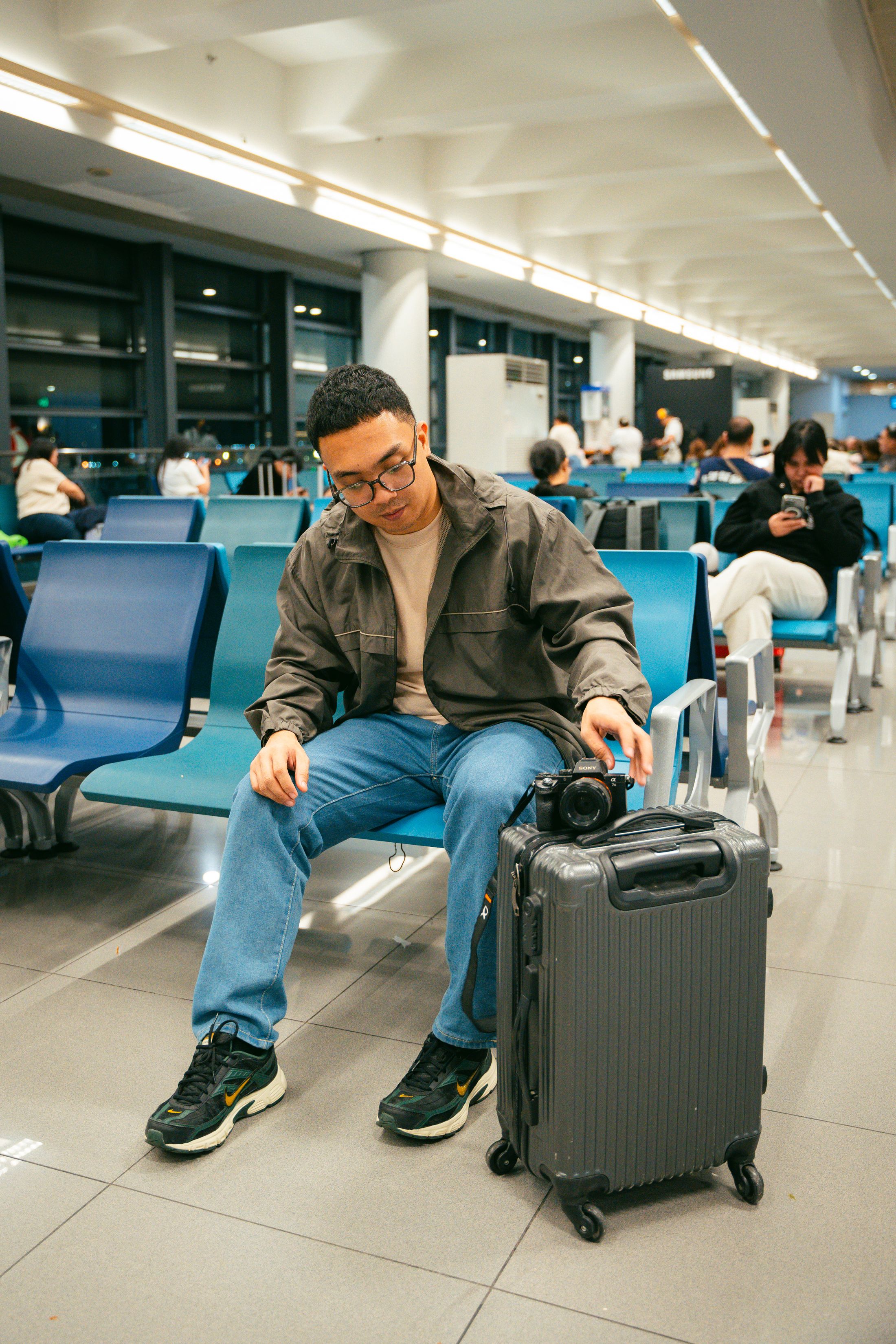 Modern traveler waiting at an airport terminal with luggage and a camera